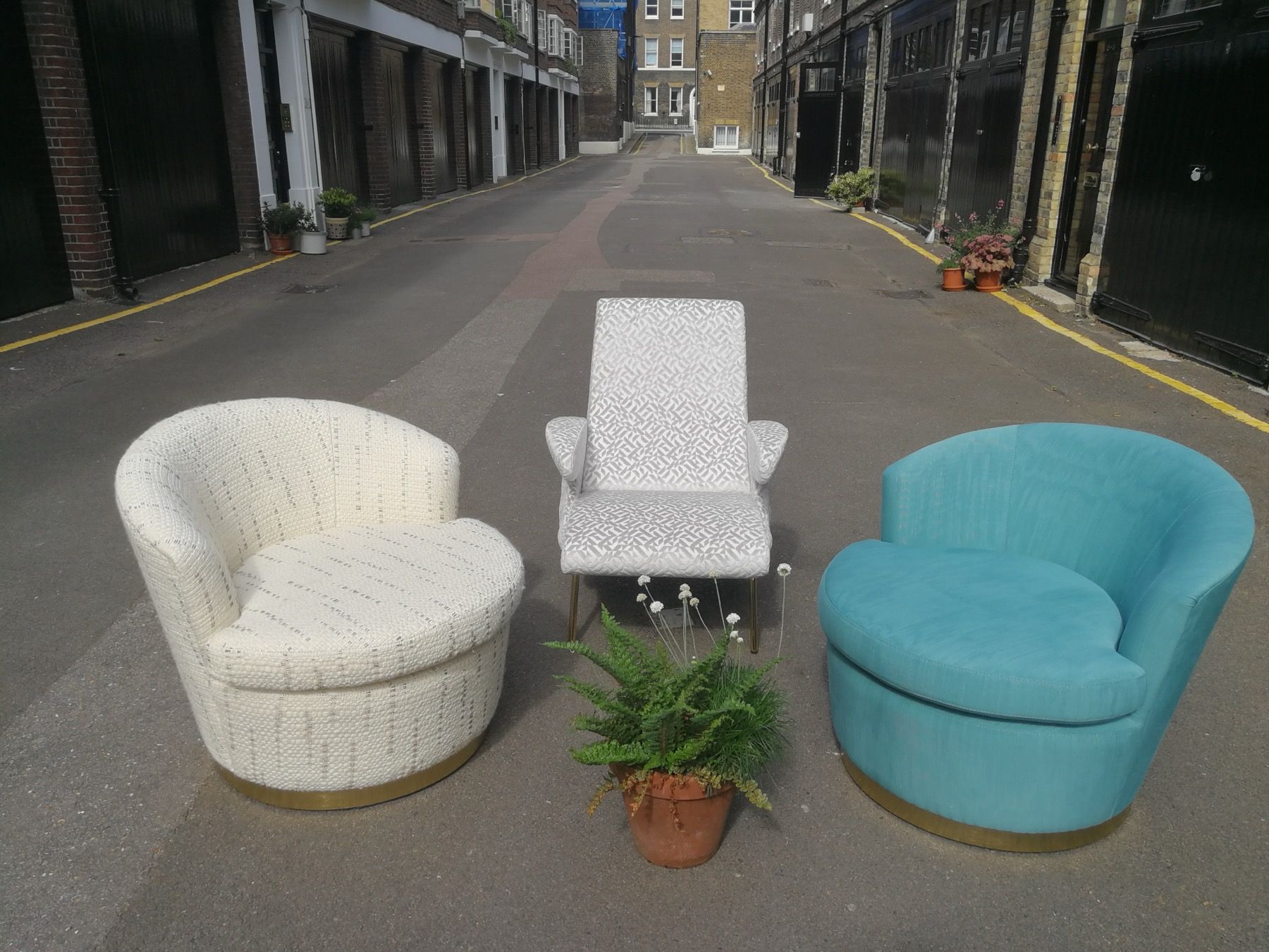 Blue and white upholstered chairs arranged around a table outside a London workshop