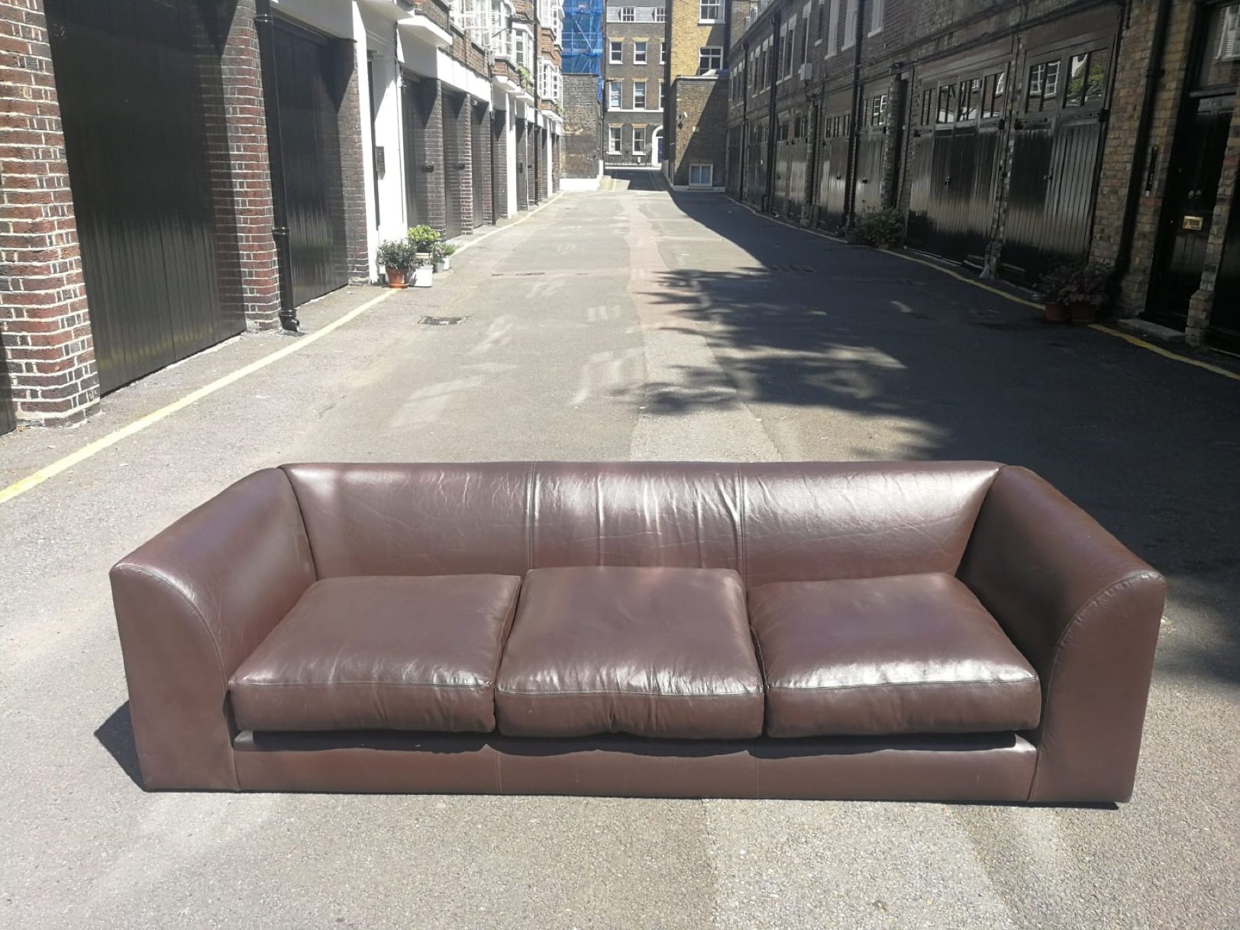 Brown leather sofa photographed in a London courtyard before leather repair or restoration assessment