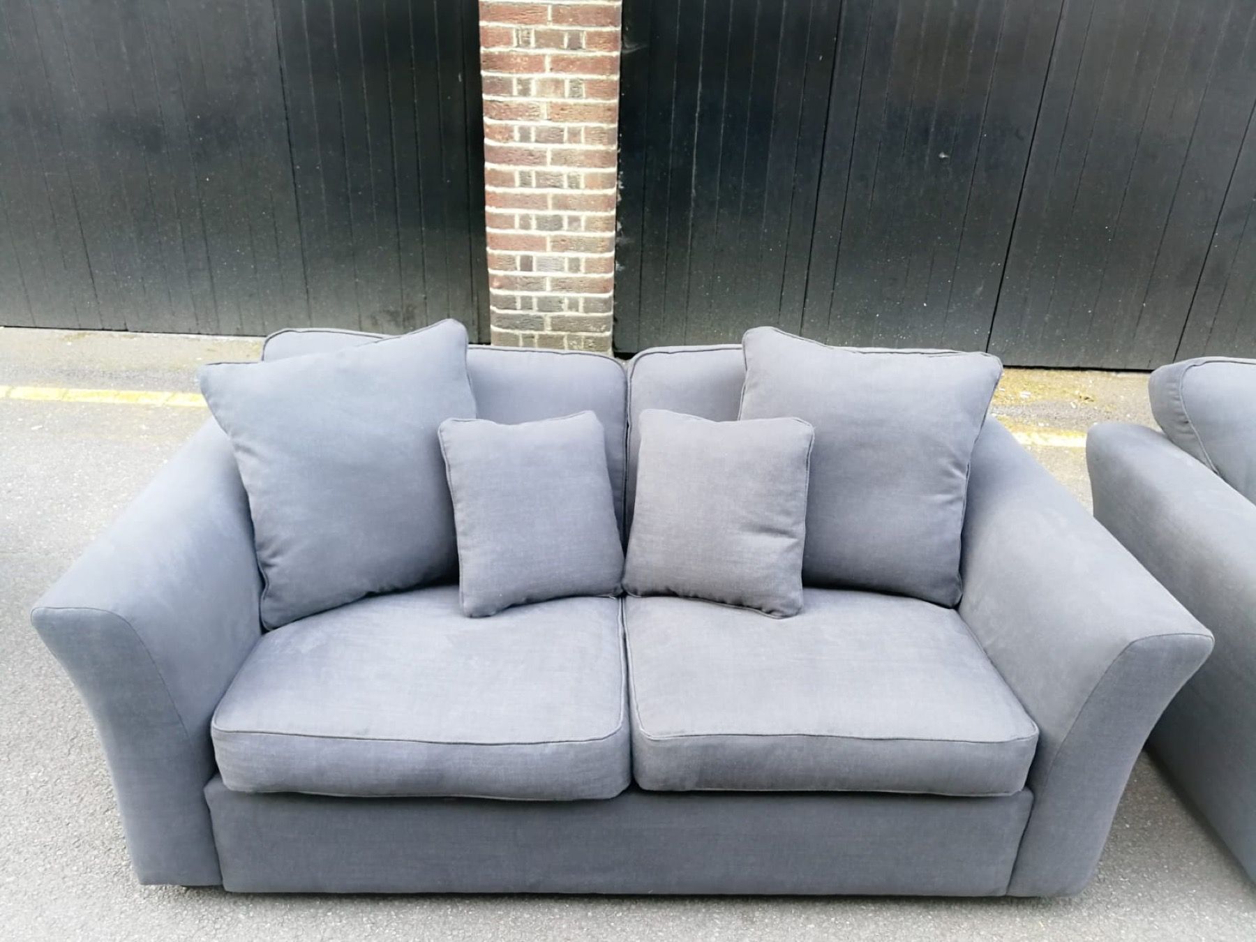 Grey reupholstered sofa with matching scatter cushions photographed outside the workshop