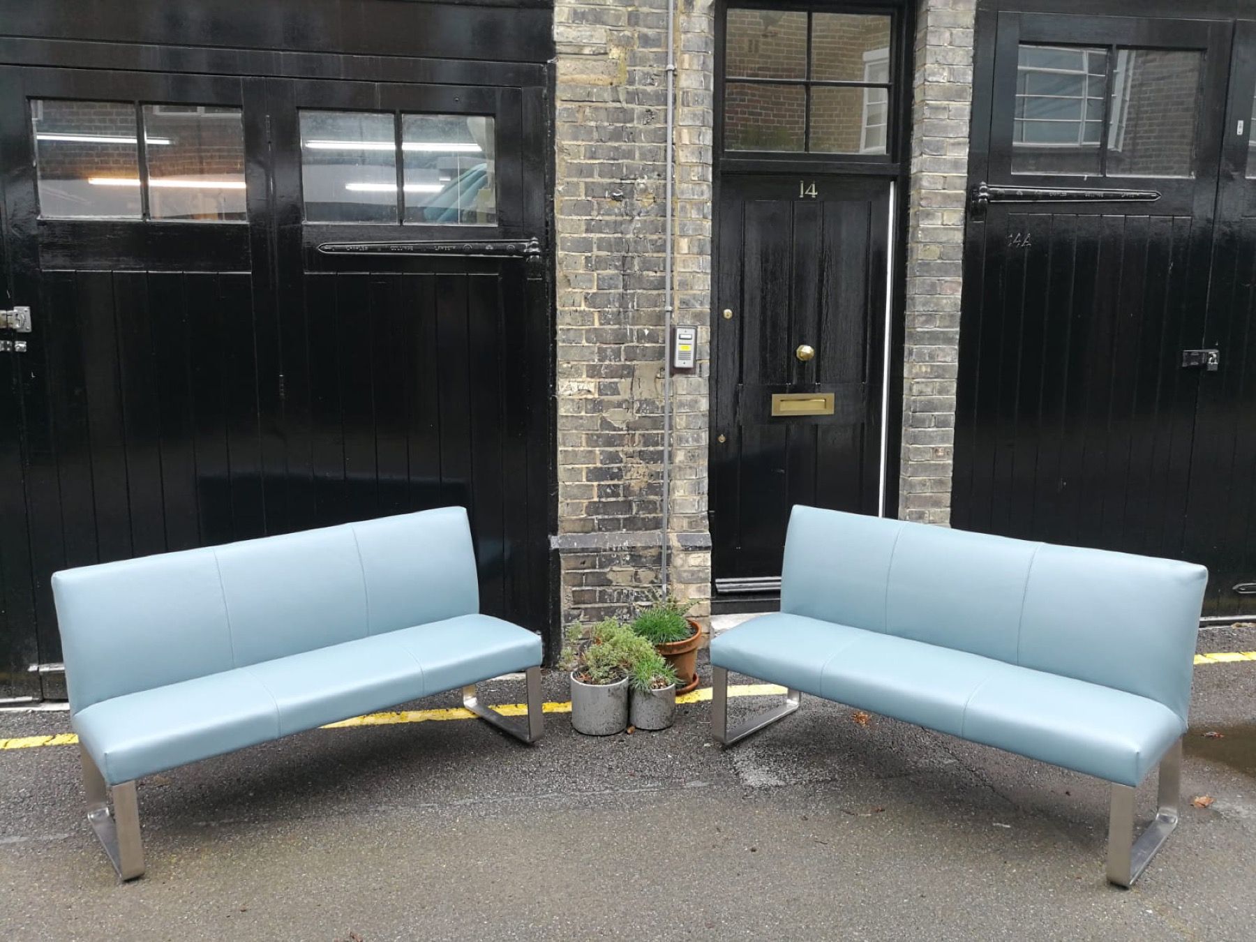 Pair of pale blue upholstered benches photographed outside a London upholstery workshop