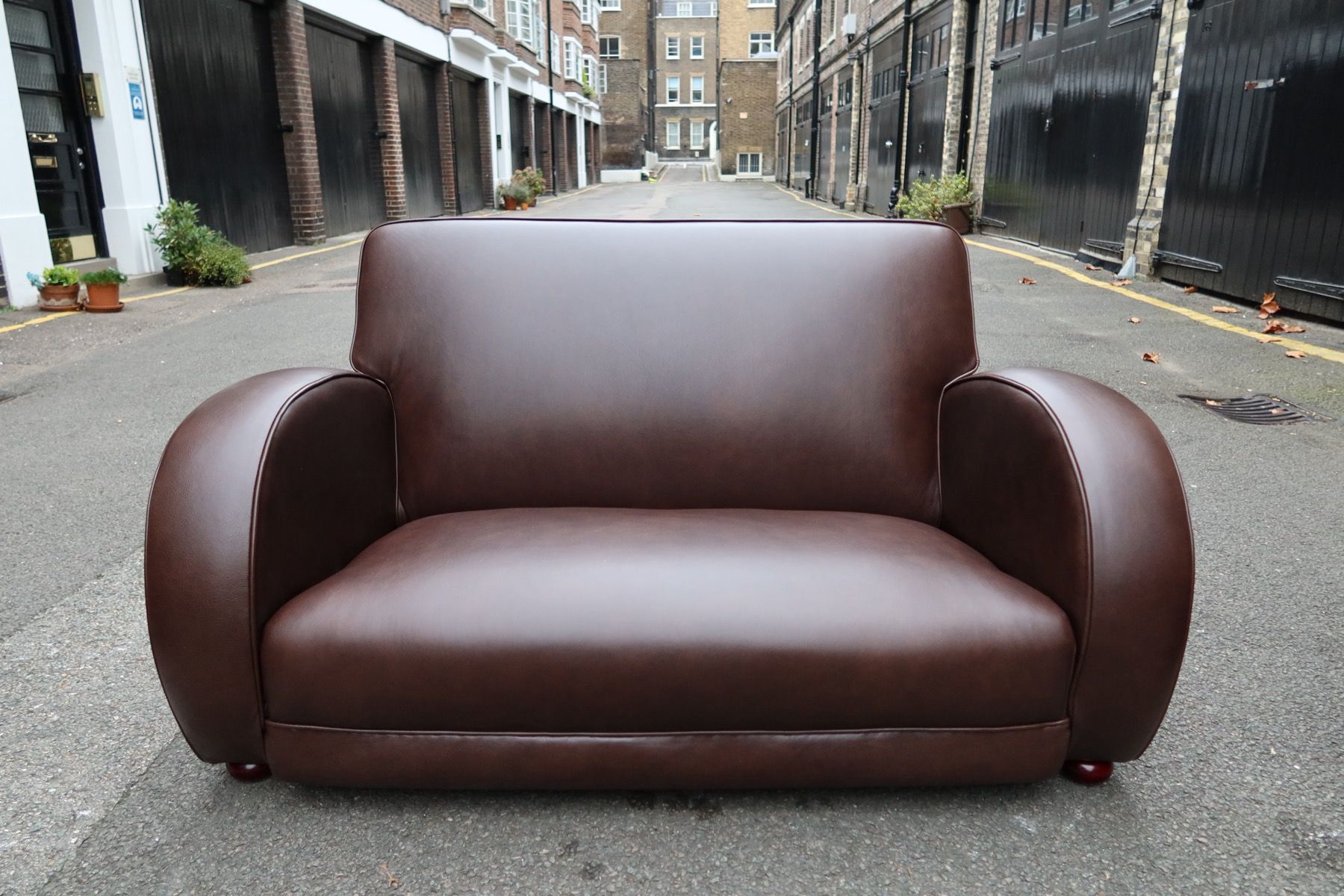 Restored brown leather sofa with smooth arms and clean stitching