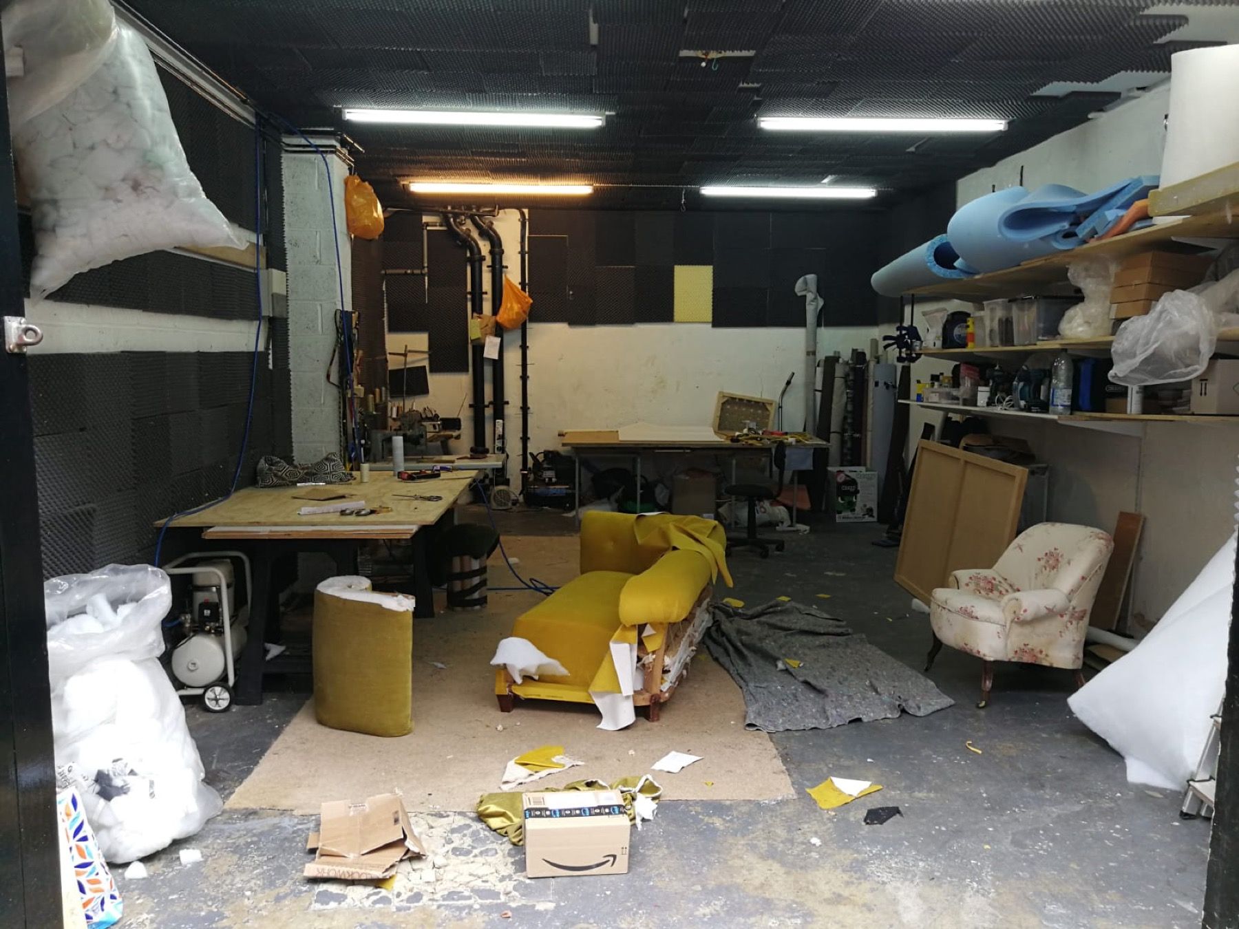 Sofa being reupholstered inside the workshop with fabric and tools nearby